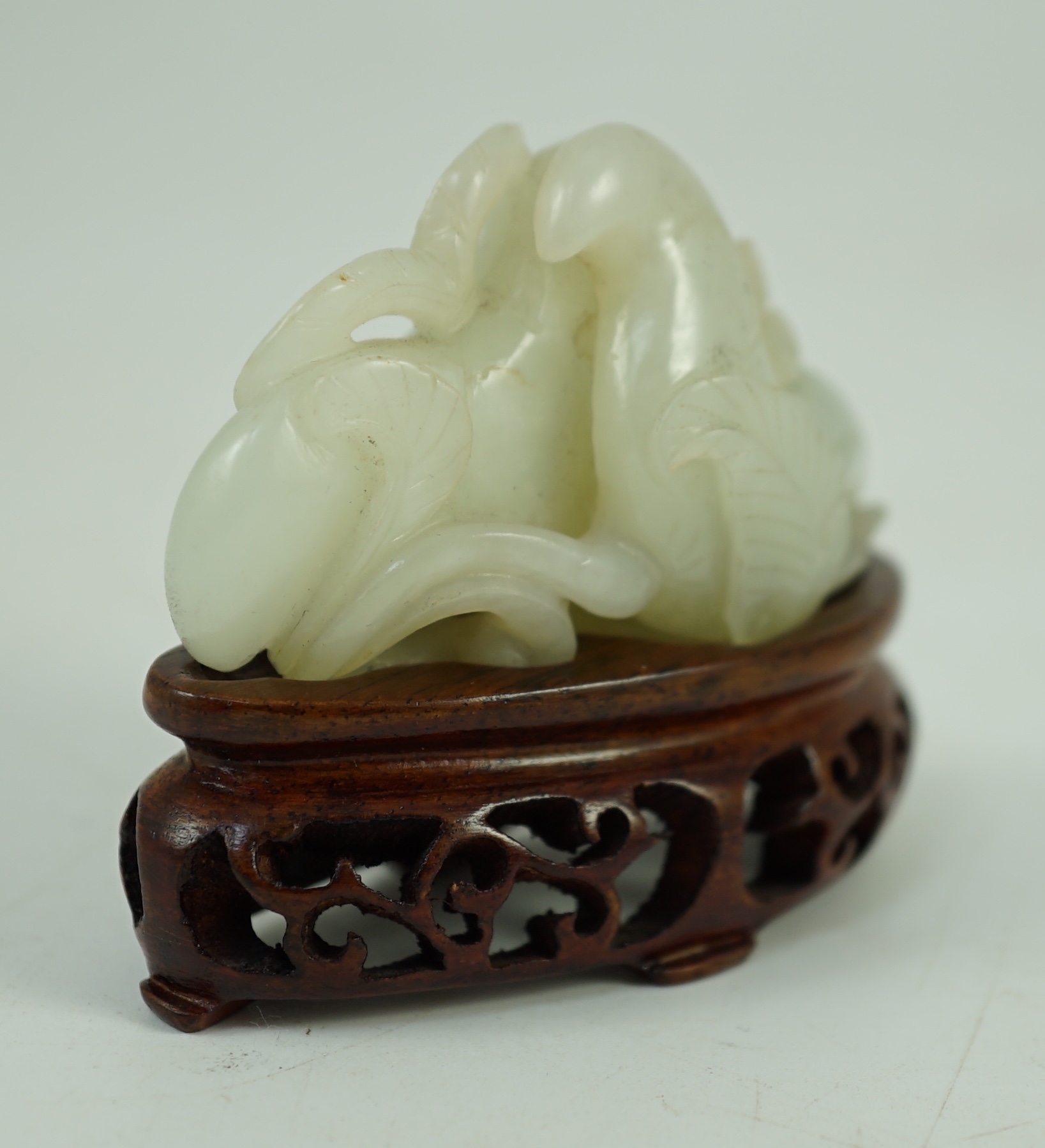 A Chinese pale celadon jade ‘Lotus’ pebble carving, 18th/19th century, 6.2 cm wide, wood stand